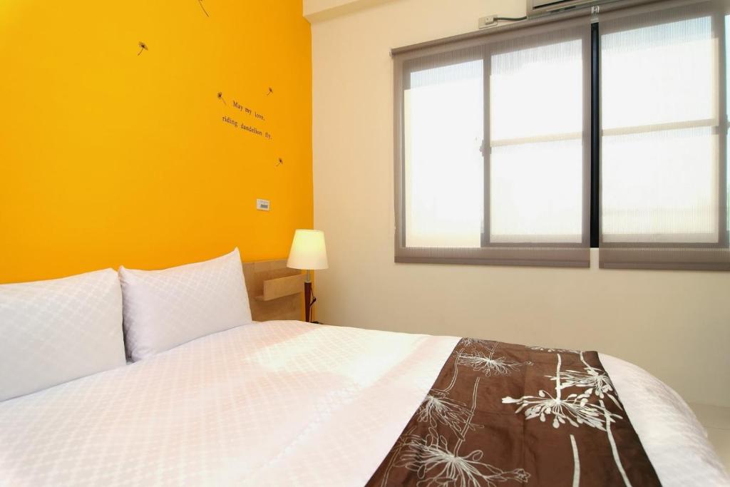a bedroom with a white bed and a window at Plentiful-Inn Kenting in Hengchun South Gate