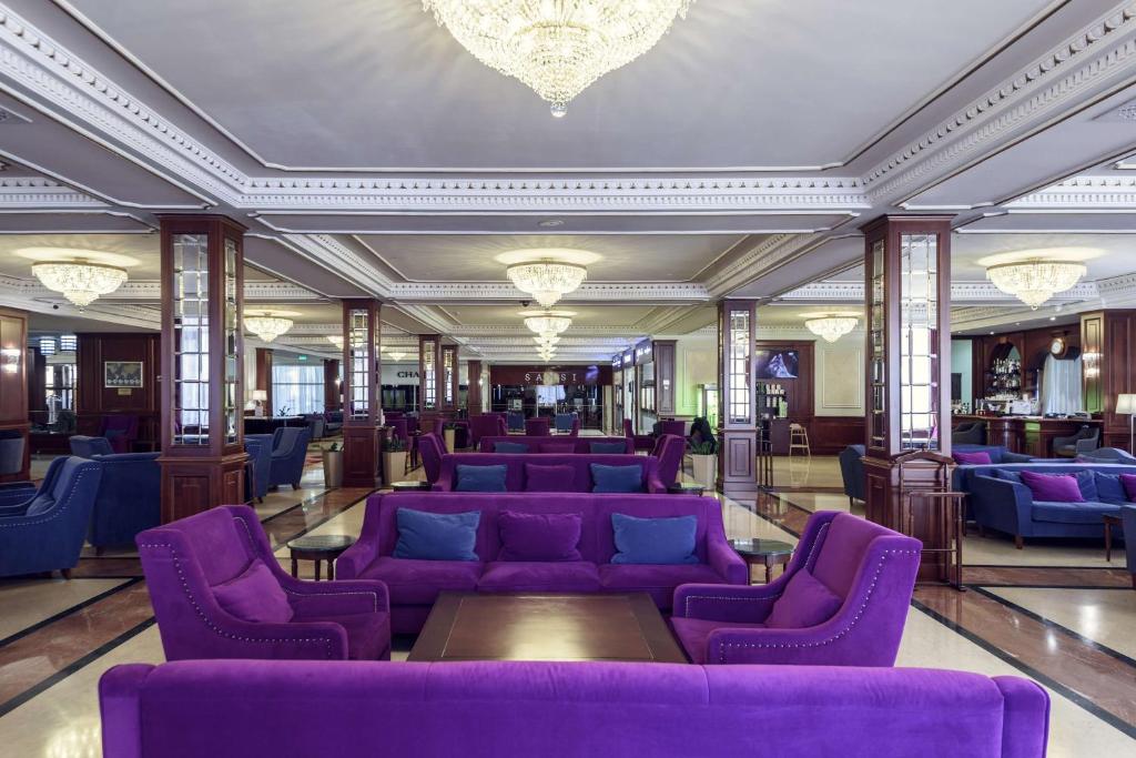 a lobby with purple couches and tables in a building at Radisson Hotel Astana in Astana