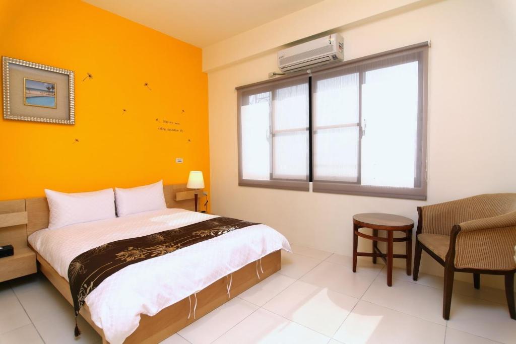 a bedroom with a bed and a window and a chair at Plentiful-Inn Kenting in Hengchun South Gate