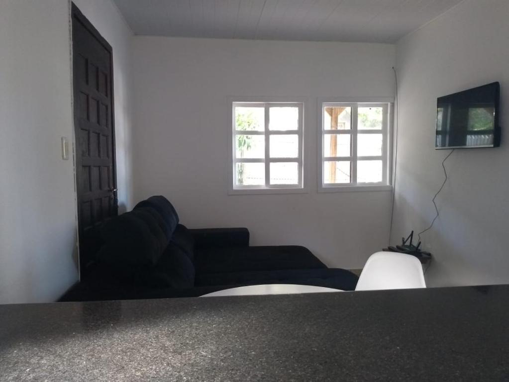 a living room with a couch and two windows at Casa Refúgio Praia Brava in Itajaí