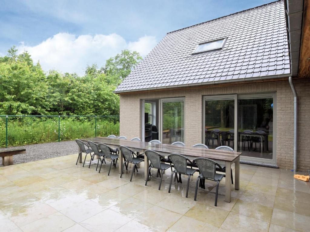 een lange houten tafel en stoelen op een patio bij Luxurious Home with Sauna in Somme-Leuze