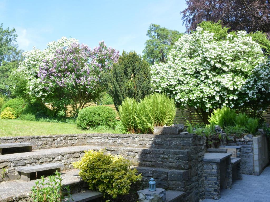 una pared de piedra en un jardín con flores en Delightful Holiday Home in Denee With Terrace, en Denée