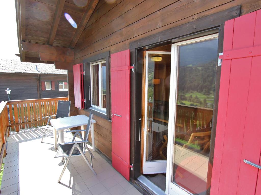 フィエッシュにあるAttractive chalet in Fiesch Wiler with viewsの赤いドア、テーブル、椅子付きのデッキ