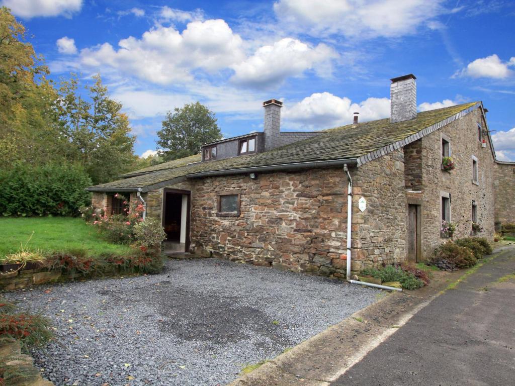 an old stone house with a gravel driveway at Farmhouse situated at the edge of the woods in Manhay