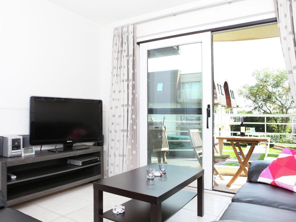 布雷德內的住宿－Stylish Apartment in Bredene with Pool，客厅配有平面电视和桌子。