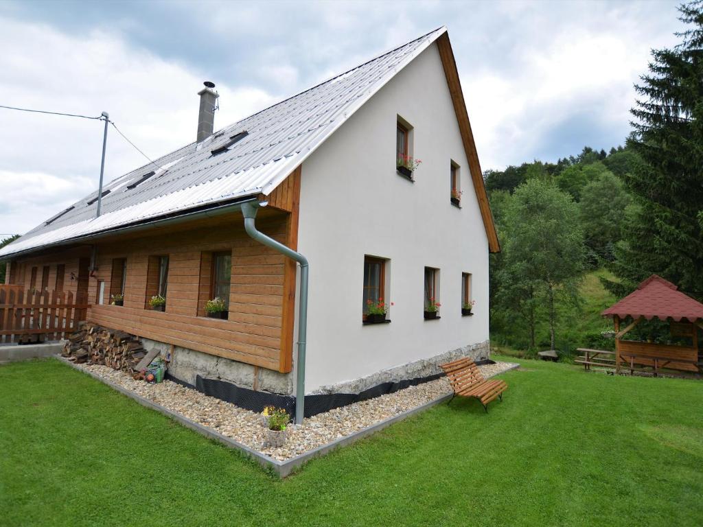 una casa blanca con techo de gambrel y un banco en holiday home with sauna and billiards ski slope, en Rudolfov