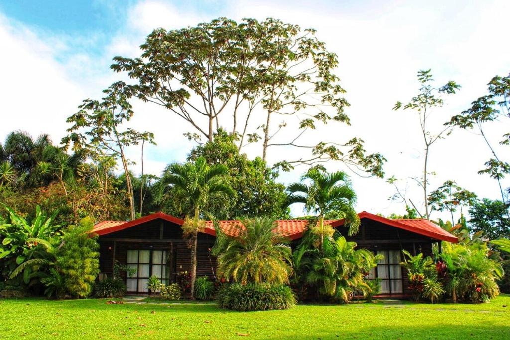 a house with a red roof in the grass at Casona Rústica & Bungalow in Fortuna