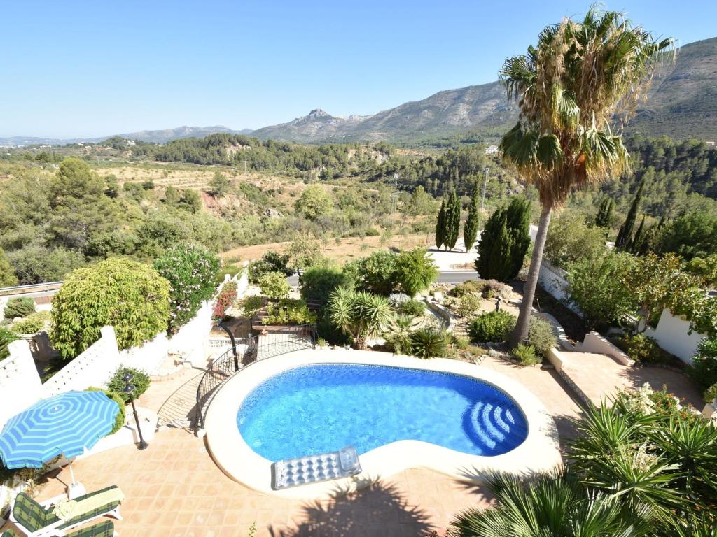 a swimming pool in a garden with a palm tree at Belvilla by OYO Villa Antonio Alto 4 pax in Benichembla