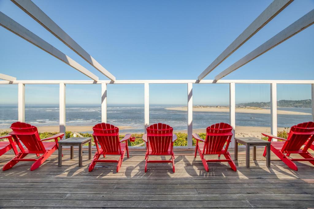 沃德波特的住宿－Cliff House - Waldport，甲板上一组红色的椅子和桌子
