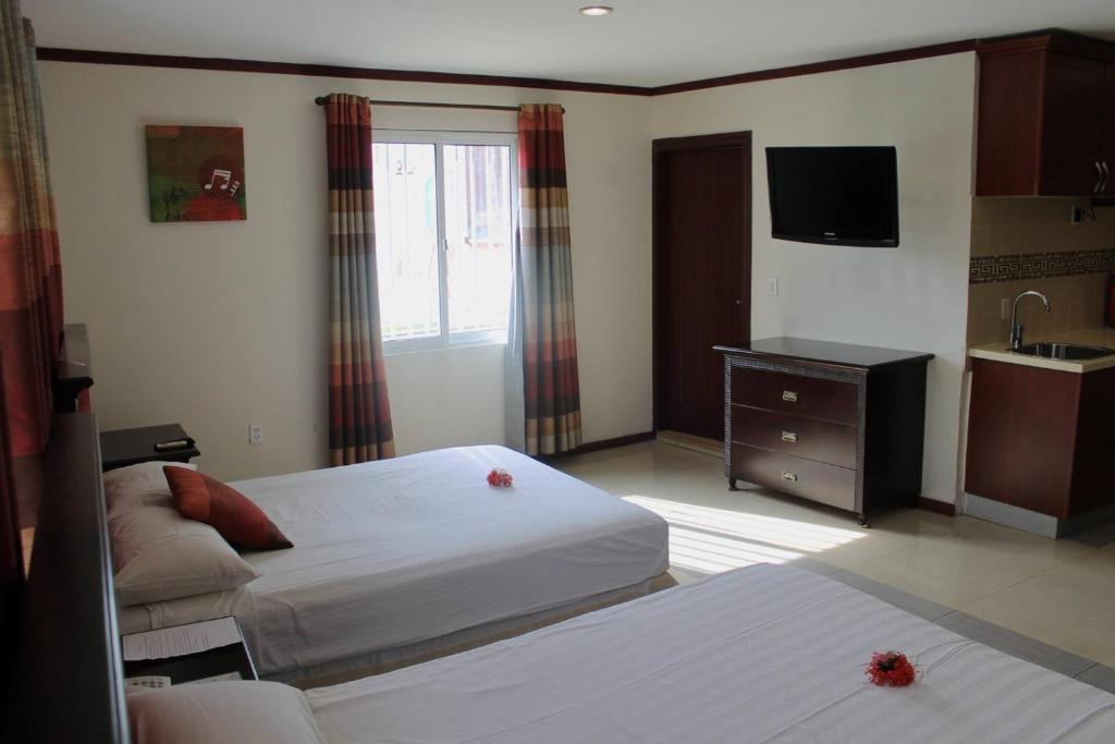 Habitación de hotel con 2 camas y TV en Curacao Suites Hotel, en Willemstad
