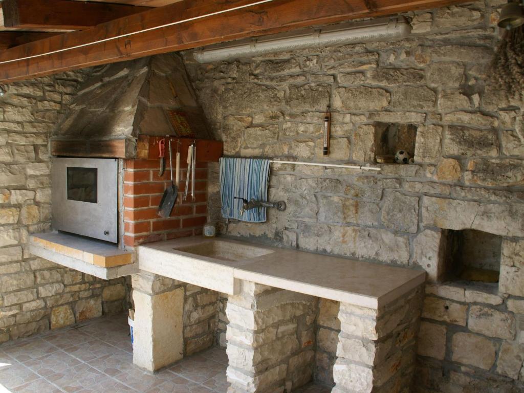 een stenen keuken met een aanrecht en een oven bij Traditional villa with private pool in Peresiji