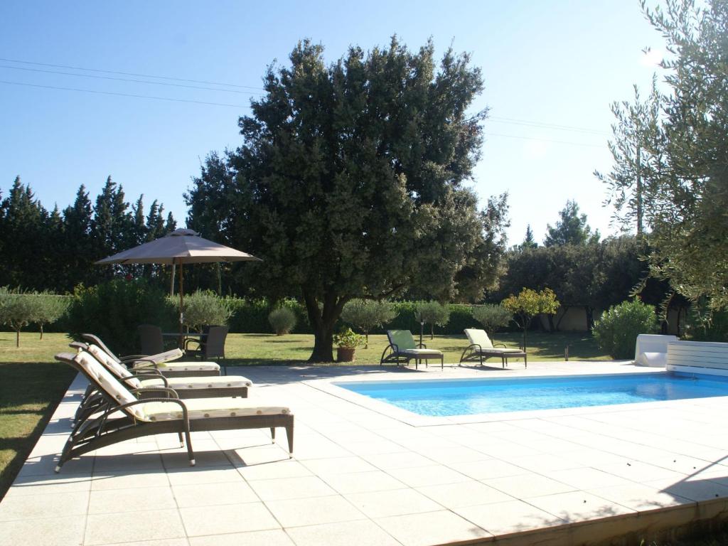 BédarridesにあるStunning Villa in Sorgues with Swimming Poolのラウンジチェアとパラソル付きのスイミングプールを併設しています。