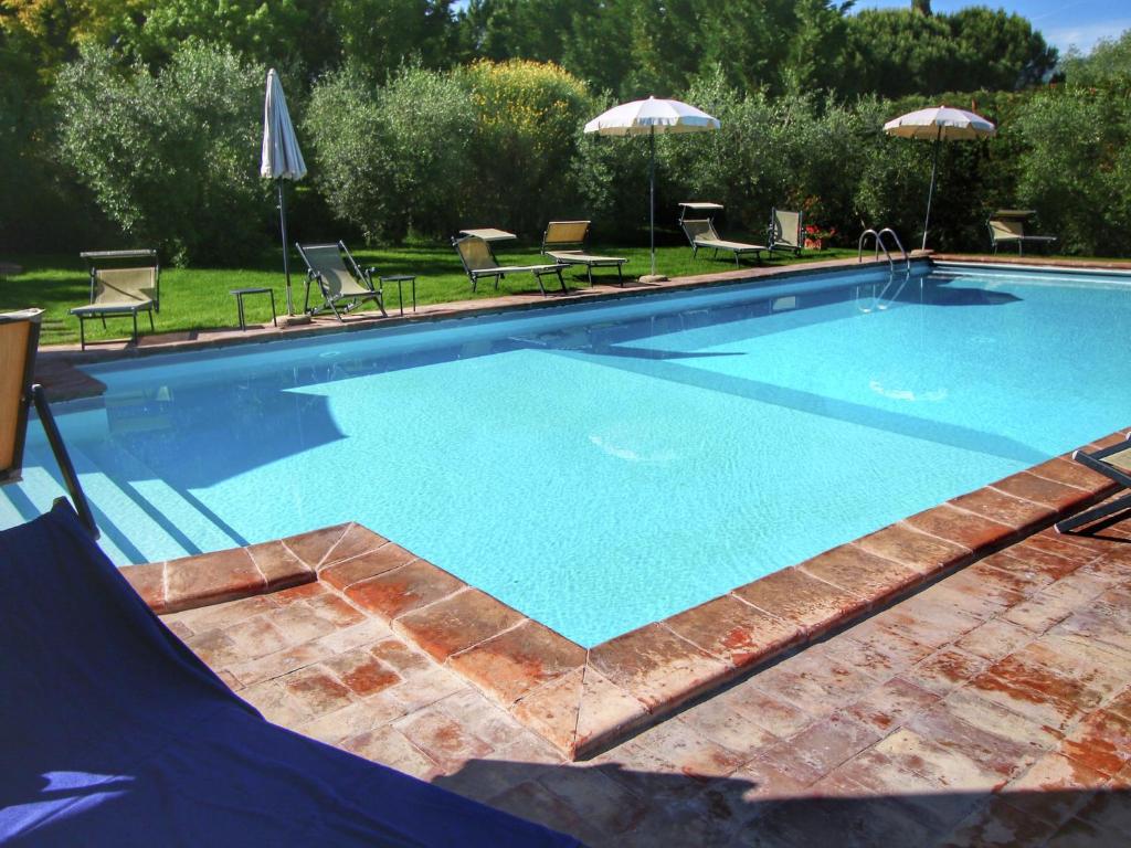 a large swimming pool with chairs and umbrellas at Belvilla by OYO Cipresso in Cortona