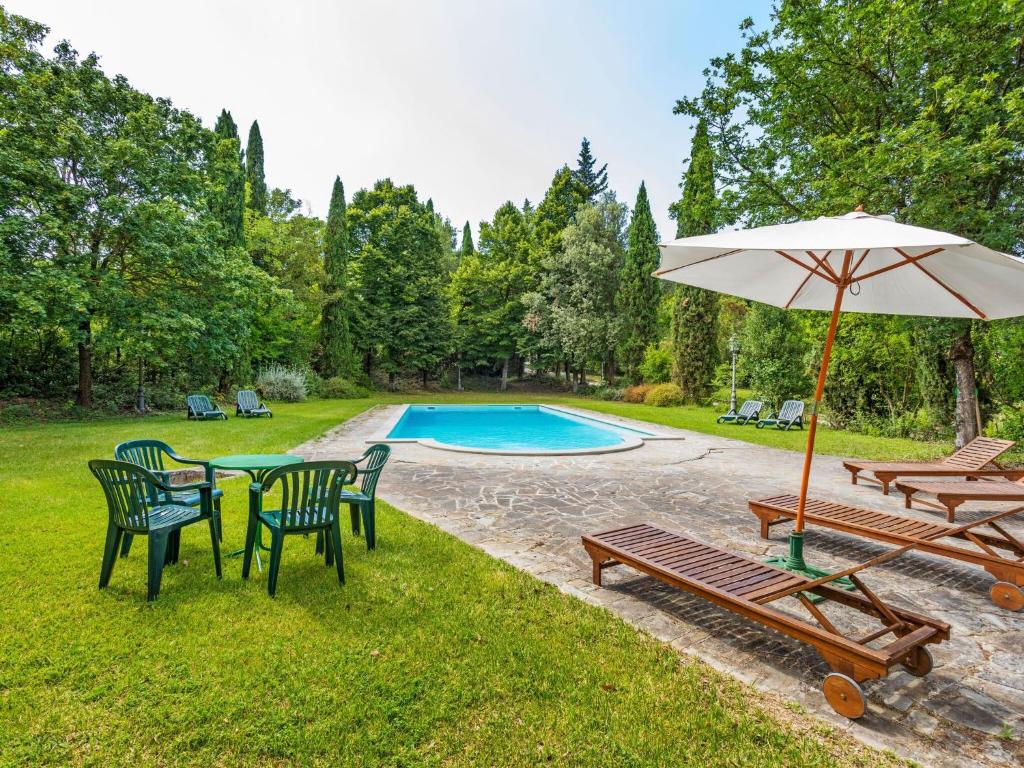 een tafel en stoelen met een parasol en een zwembad bij Belvilla by OYO A recently renovated countryhouse in Perugia