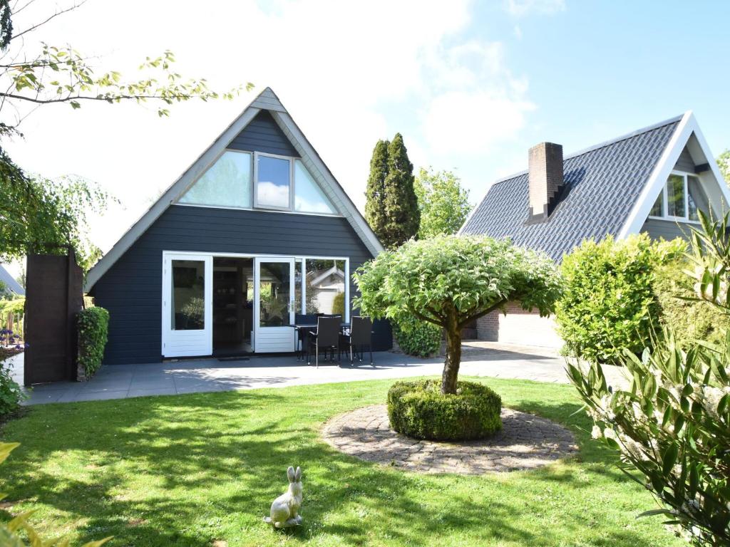 ein Haus mit einem Baum im Hof in der Unterkunft Balmy Holiday Home in Tuitjenhorn with Fenced Garden in Tuitjenhorn