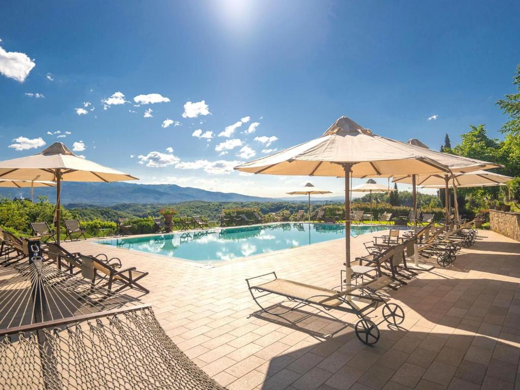 a swimming pool with chairs and umbrellas at Stunning Holiday Home in Figline Valdarno with Barbecue in Figline Valdarno
