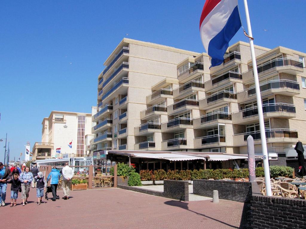 un gran edificio con una bandera delante de él en Apartment at the promenade and beach, en Noordwijk