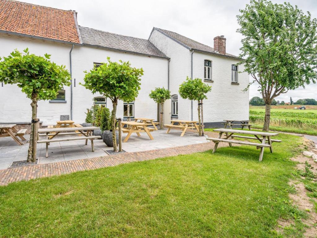 a patio with picnic tables and trees in front of a building at Spacious farmhouse in Limburg near forest in Sint Antoniusbank