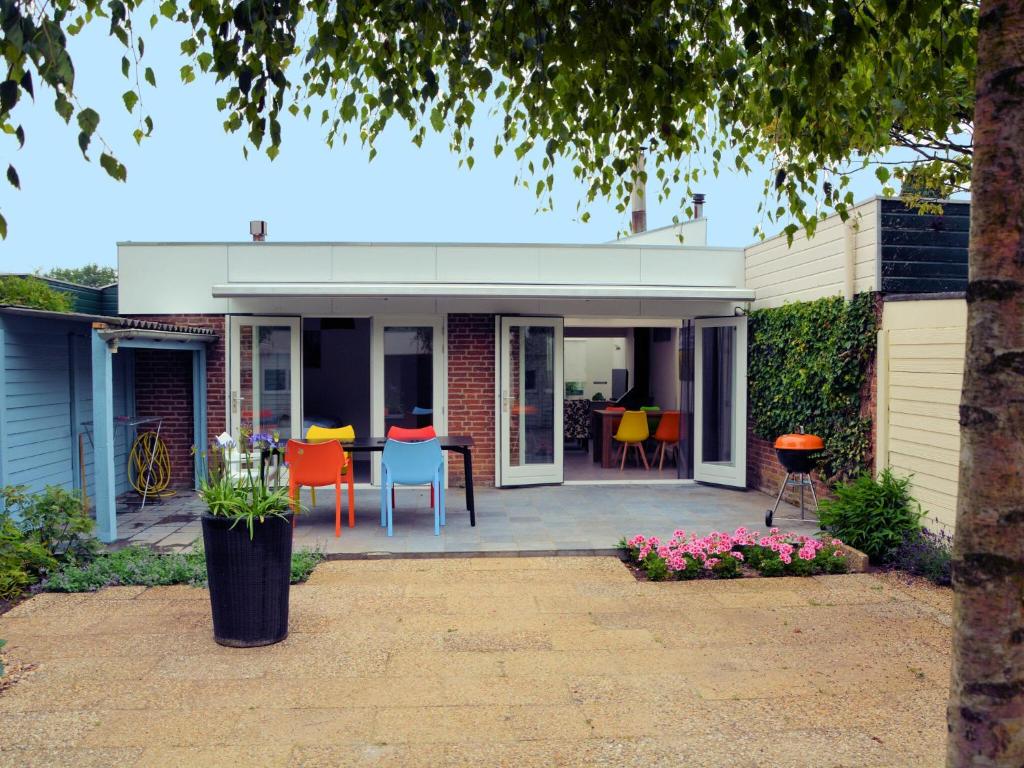 Cette maison dispose d'une terrasse avec des chaises et une table. dans l'établissement Fresh and colorful holiday home near the beach sea dunes and lake, à Noordwijkerhout