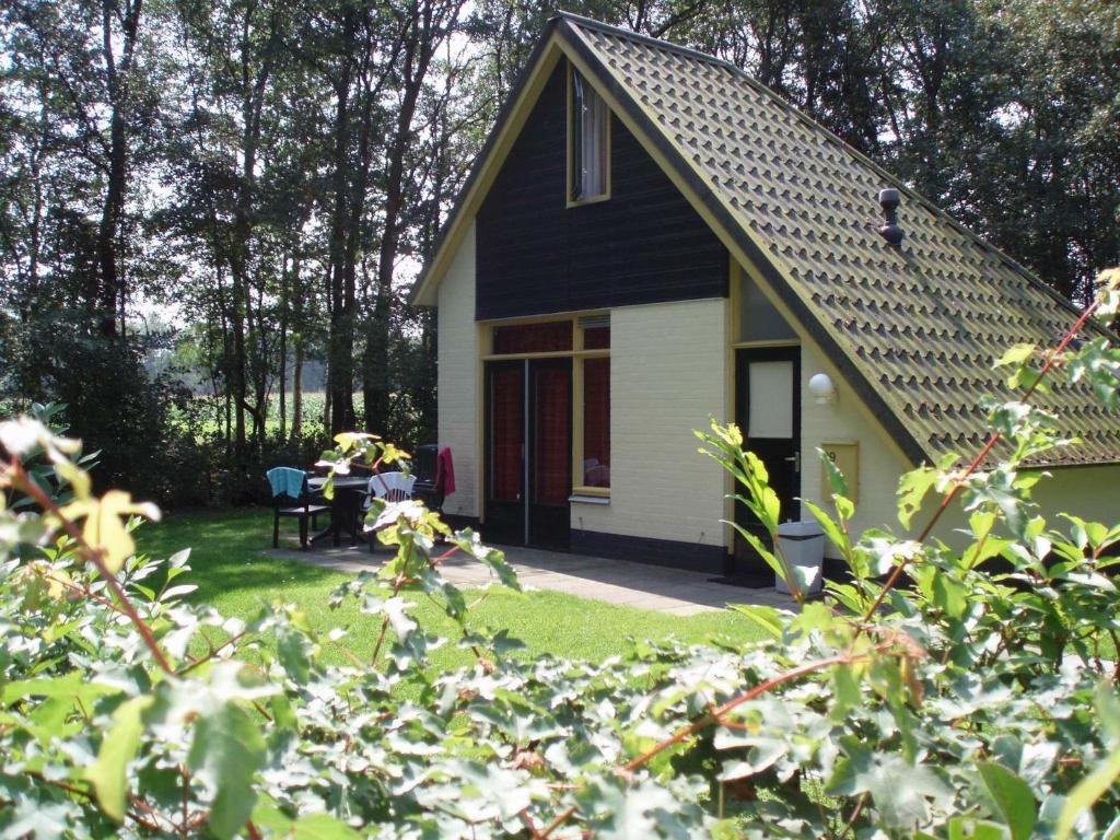 uma casa a preto e branco com uma mesa e cadeiras em Attractive holiday home with large garden, near Zwolle em Dalfsen