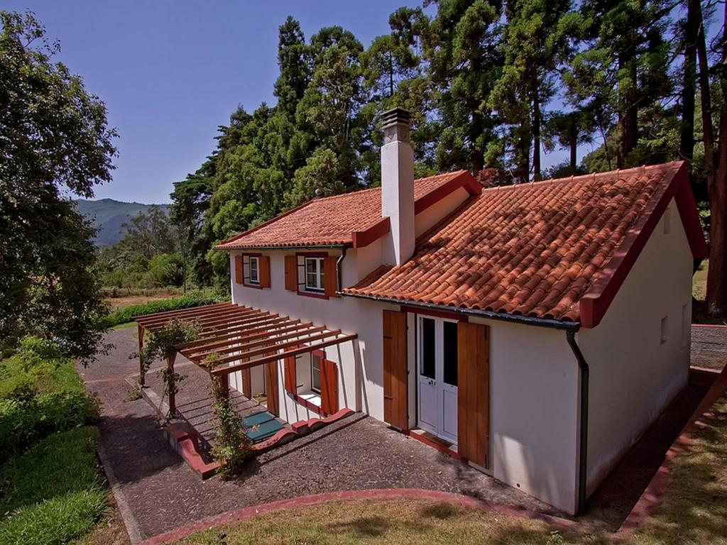 una pequeña casa blanca con techo rojo en Quinta Das Colmeias Cottage en Santo da Serra