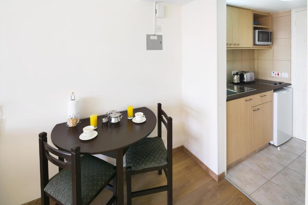 a dining room table with two chairs and a kitchen at Club Aphrodite in Erimi