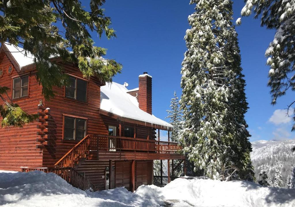 a log cabin in the snow with a deck at Scenic Wonders & Apt. in Yosemite West