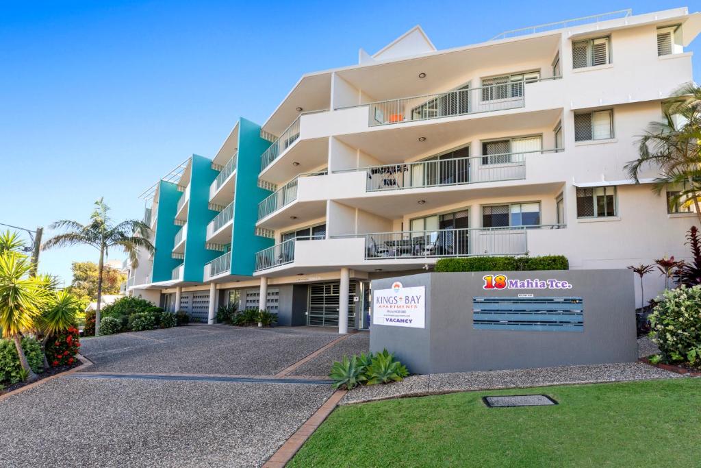 a large apartment building with a sign in front of it at Kings Bay Apartments in Caloundra