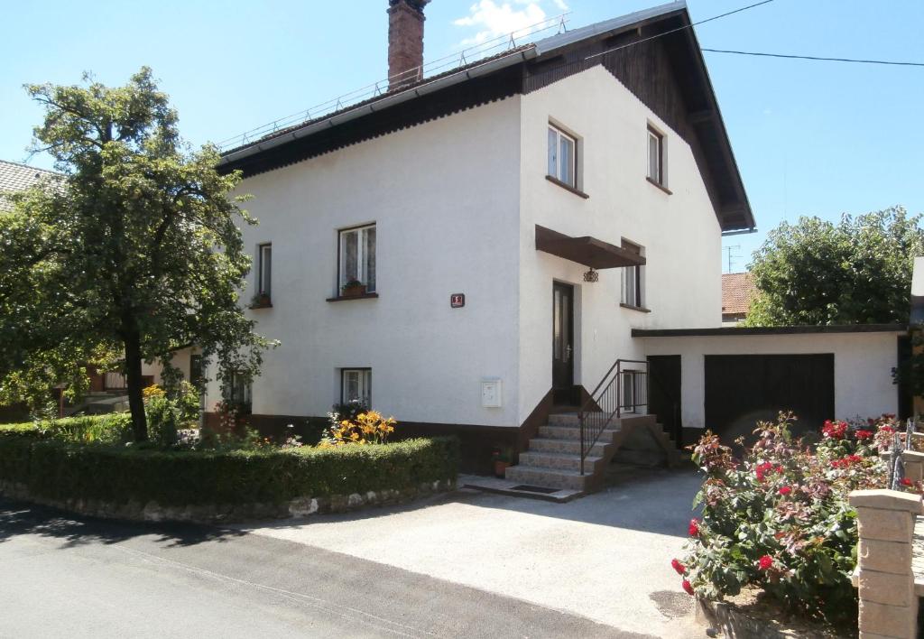 a white house with a garage and some flowers at Rooms Apartma Cerknica in Cerknica