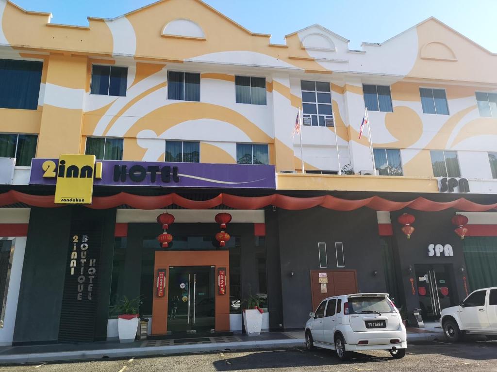 un coche blanco estacionado frente a un hotel en 2 Inn 1 Boutique Hotel & Spa, en Sandakan
