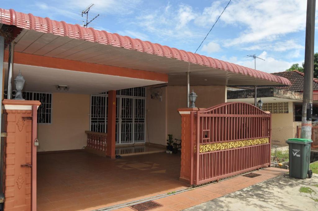 een huis met een rode poort ervoor bij Cahaya Kasih Homestay in Kangar