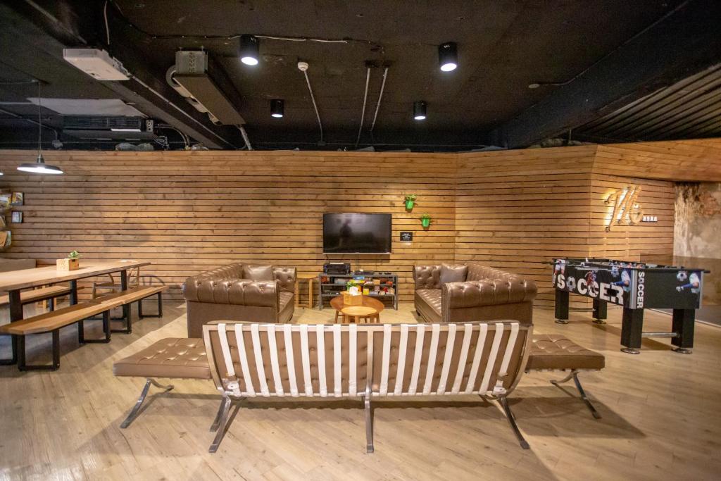 a living room with couches and a television and tables at Meander Taipei Hostel - Ximending in Taipei