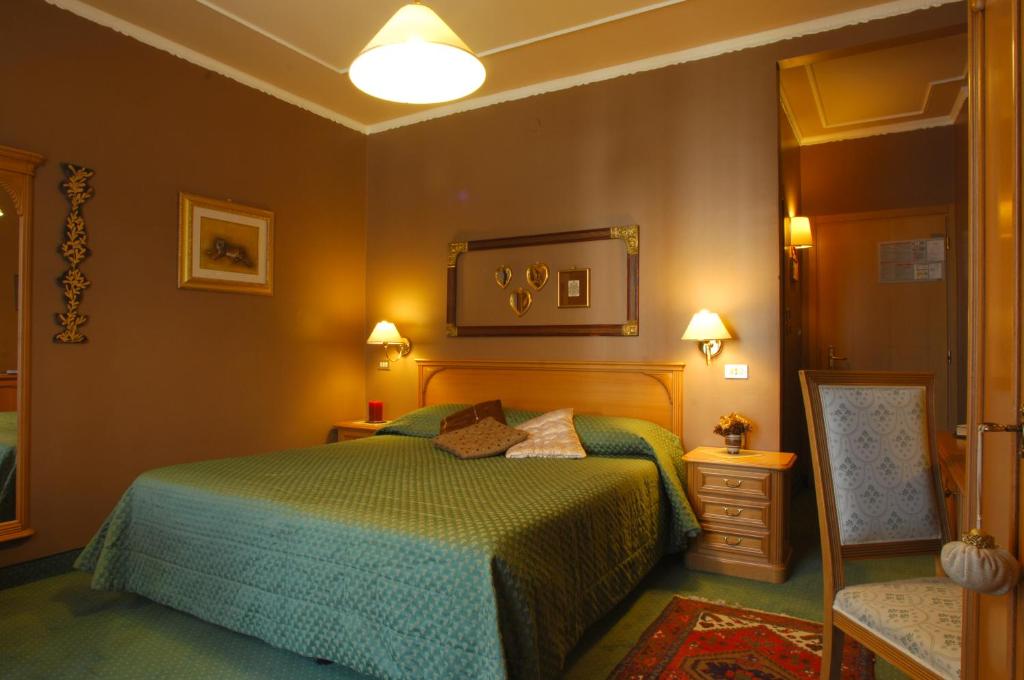 a bedroom with a green bed and a mirror at Hotel Regina in San Martino di Castrozza
