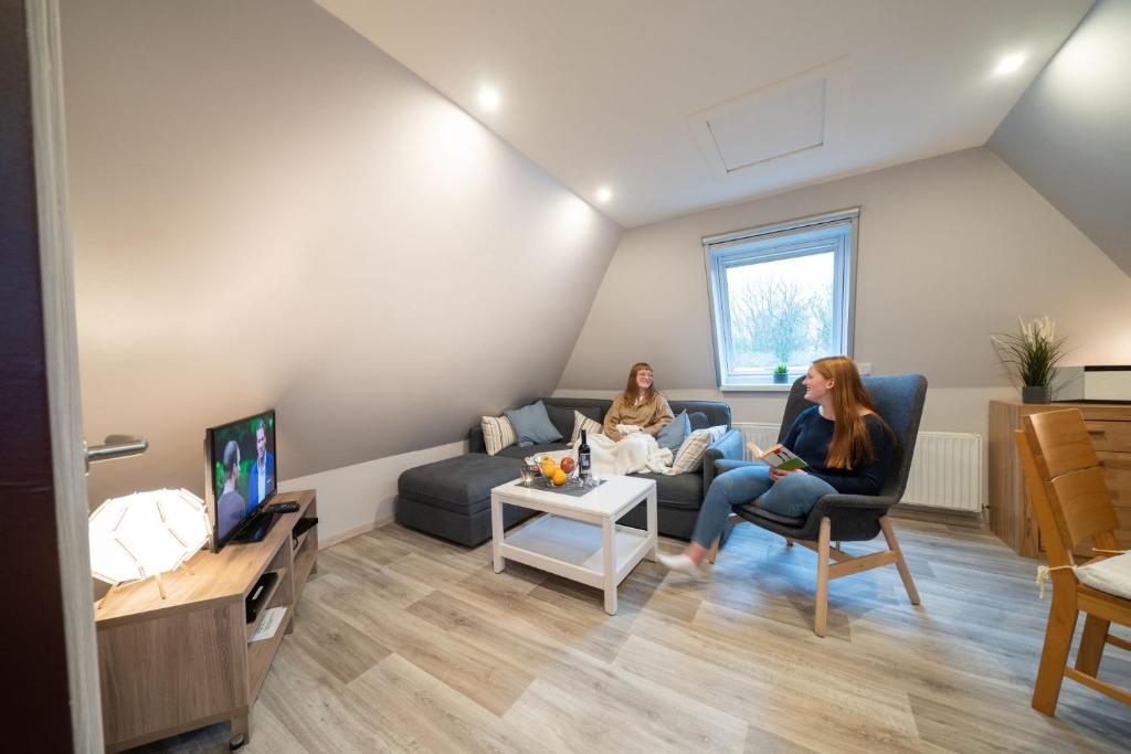 Dos mujeres sentadas en una sala viendo la tele en Ferienwohnung Kiebitz II, en Otterndorf