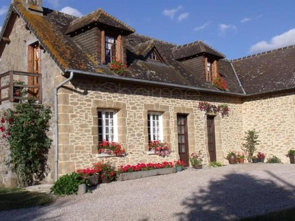 a large stone house with flowers in front of it at Le Mont Roti Chambres d’Hôtes in Faverolles