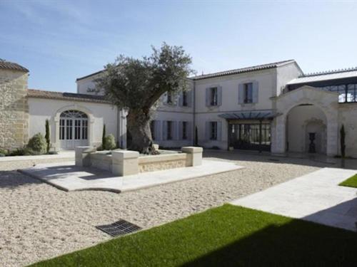 un gran edificio blanco con un árbol delante en Château La Rose Perrière en Lussac