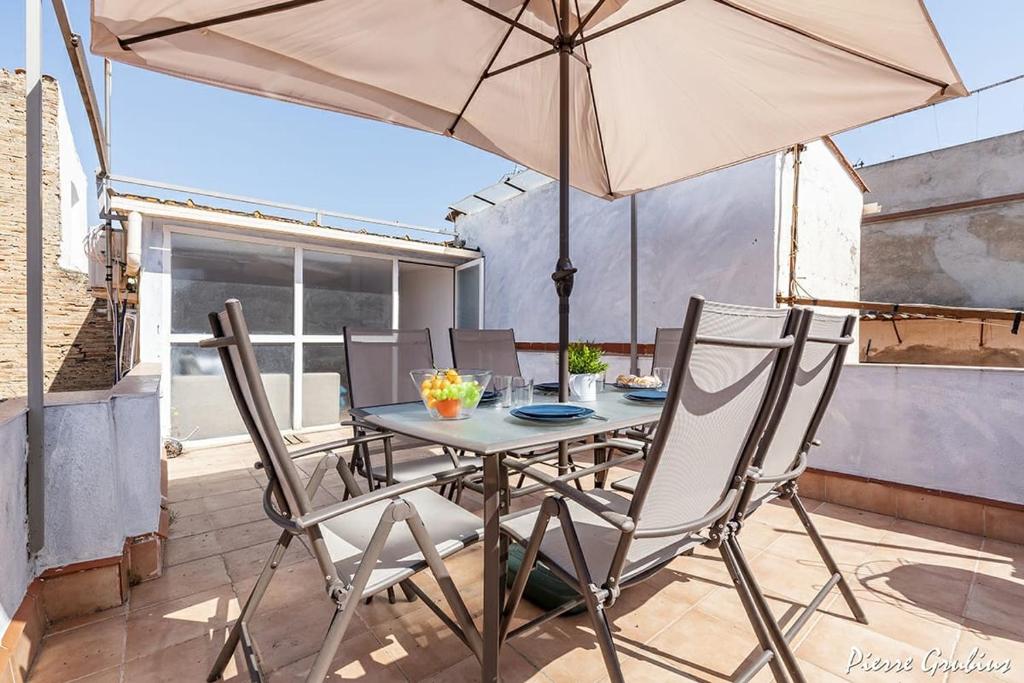 einen Tisch und Stühle mit Sonnenschirm auf einer Terrasse in der Unterkunft El Terrat de la Tecla - Dúplex Casc Antic in Tarragona