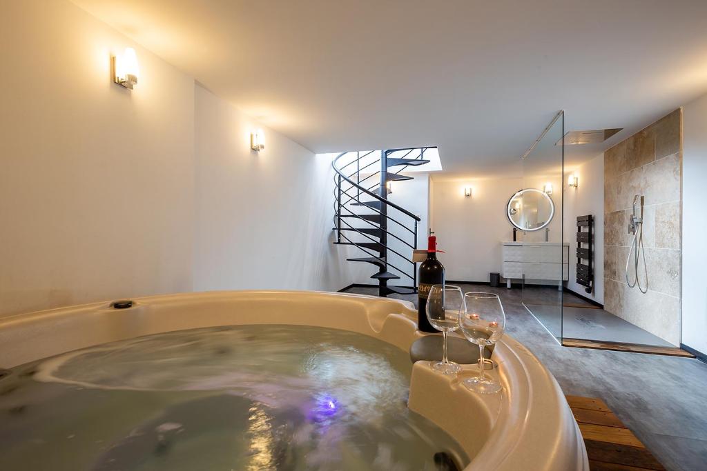 La salle de bains est pourvue d'une baignoire avec des verres à vin. dans l'établissement Mieuxqualhotel jacuzzi privatif Le rond, à Bordeaux