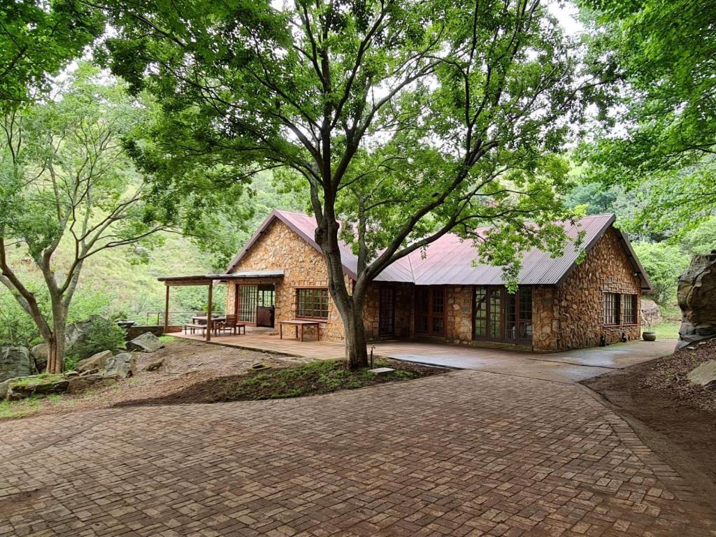 a stone house with a tree in front of it at Migrate Portfolio in Dullstroom