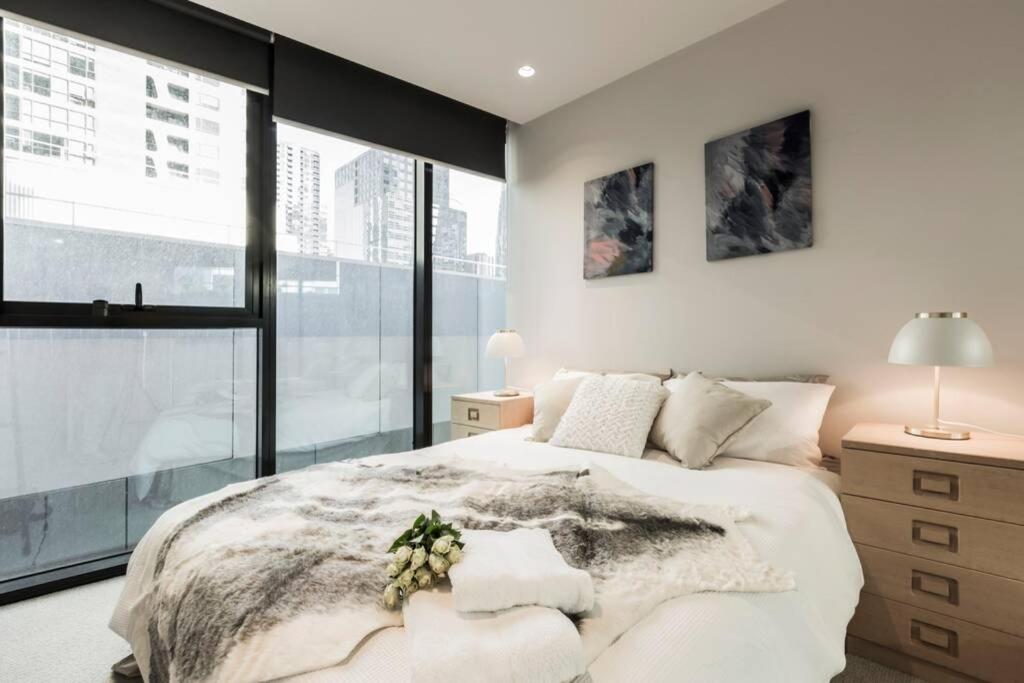 um quarto com uma cama grande e uma janela grande em Central Melbourne CBD Lighthouse Apartment em Melbourne