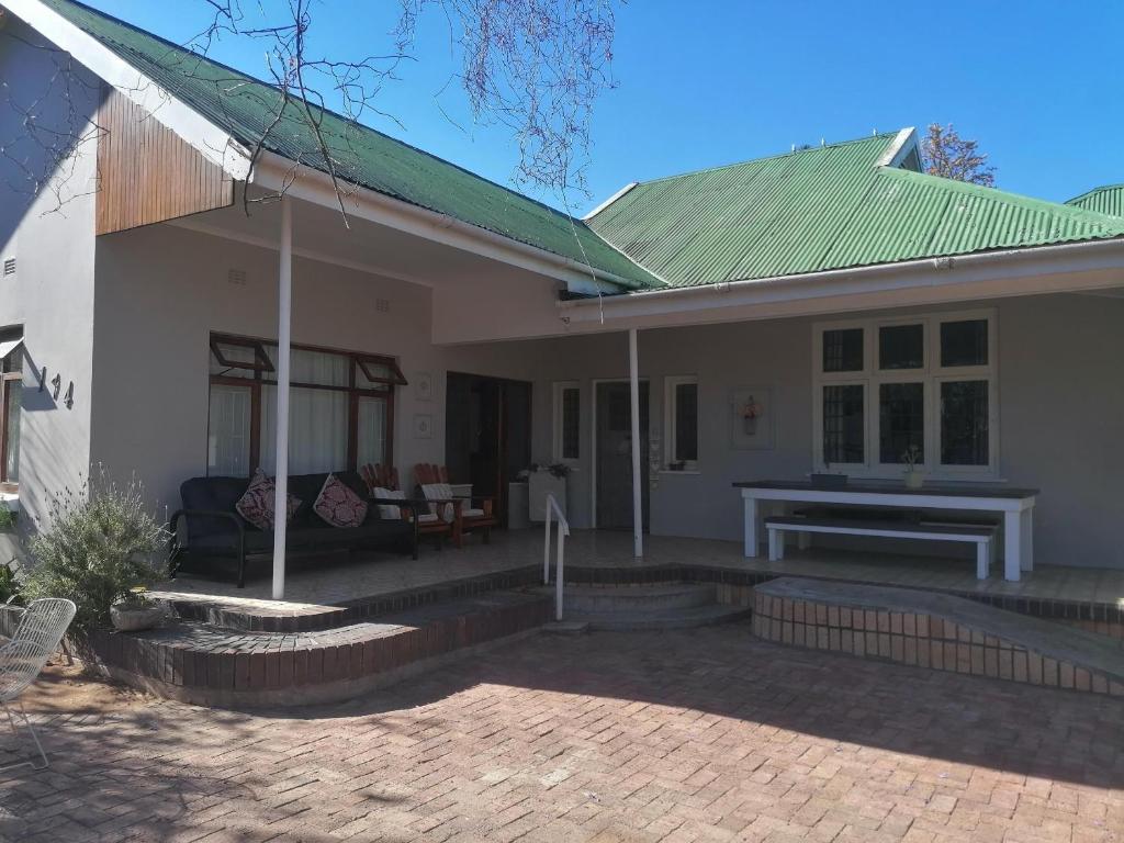 a white house with a green roof and a patio at Villa de Karoo Guest House in Oudtshoorn