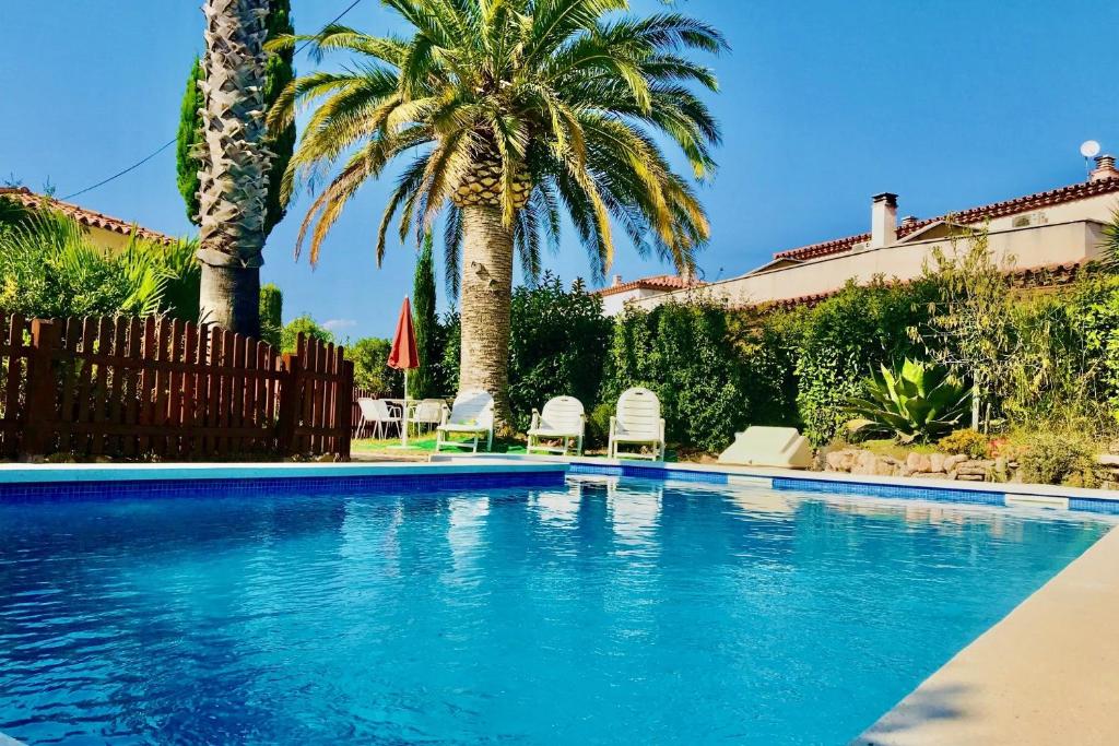 una piscina con palmeras y una valla en MEDDAYS VILLA SAMY, en Miami Platja