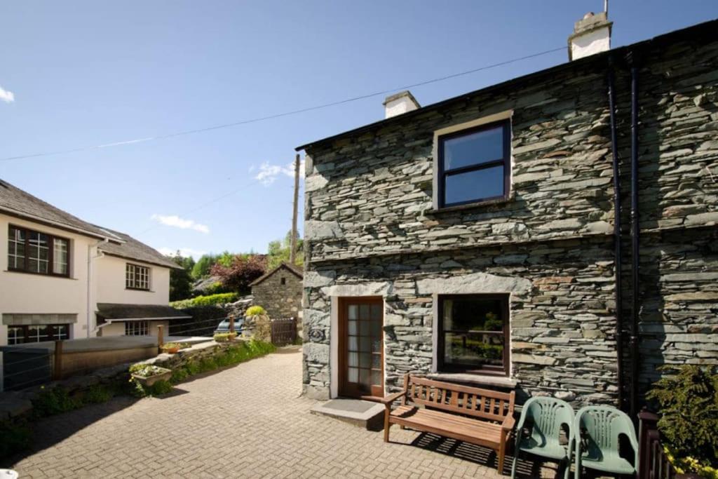 un bâtiment en pierre avec un banc et deux chaises dans l'établissement Langstrath, Chapel Stile, à Chapel Stile