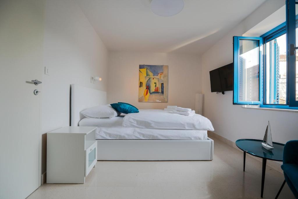ein weißes Schlafzimmer mit einem Bett und einem Tisch in der Unterkunft Hvar Old Dalmatian House Junior Suite - Deck 3 in Hvar