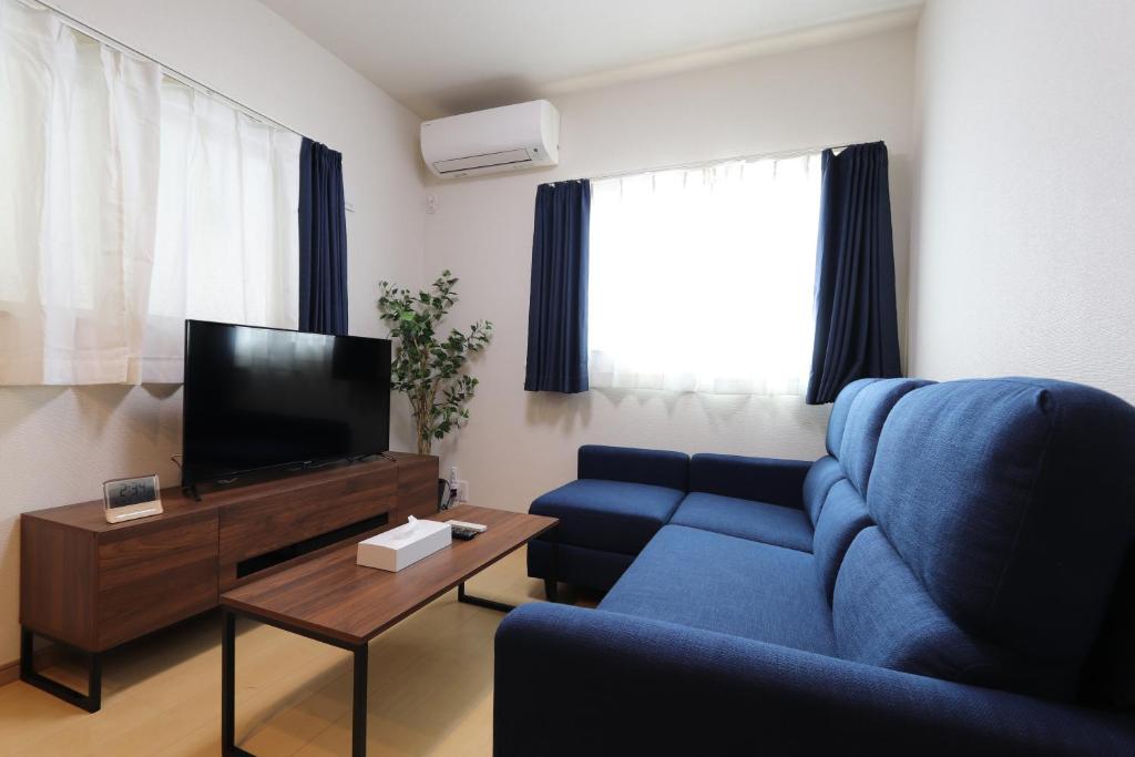uma sala de estar com um sofá azul e uma televisão em 5 minutes Shin-Osaka 3 em Osaka
