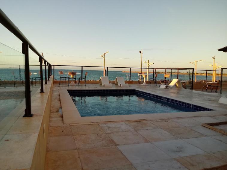 a swimming pool with chairs and a view of the ocean at Tabajara Flats Praia de Iracema in Fortaleza