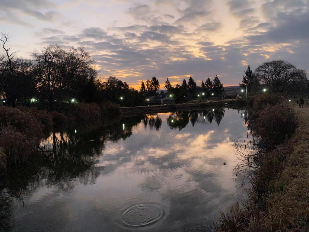 uma vista para um rio ao pôr-do-sol com nuvens no céu em Lanseria Country Estate em Lanseria