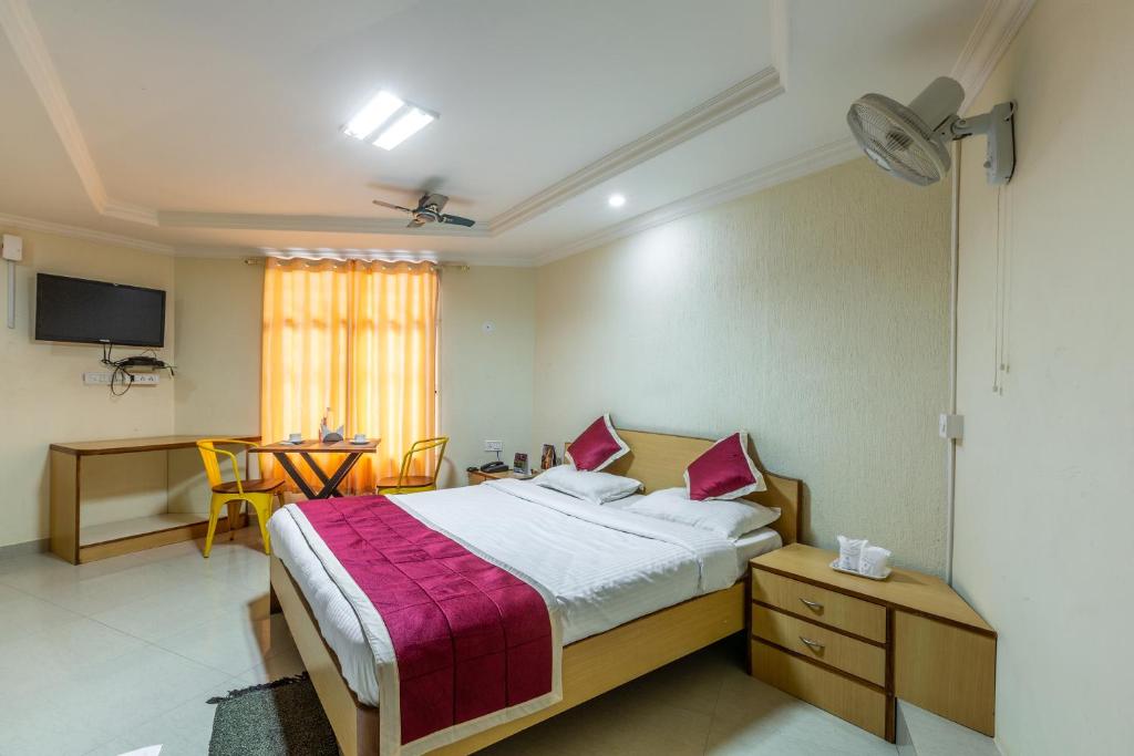 um quarto com uma cama, uma mesa e uma televisão em KSTDC Hotel Mayura Nisarga Pearl Valley em Anekal