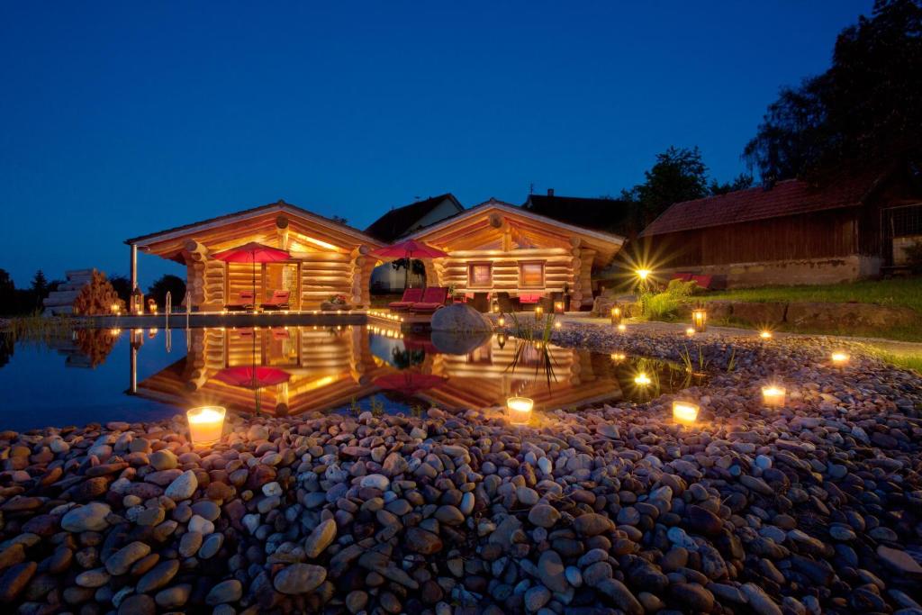 a log cabin with candles in the water at night at Hotel Konradshof in Seewald