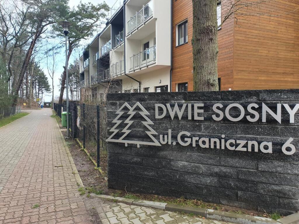 a sign on a wall in front of a building at DWIE SOSNY Apartamenty przy plaży - 365PAM in Ustronie Morskie